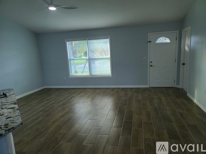 A room with a wooden floor and a window with blinds.