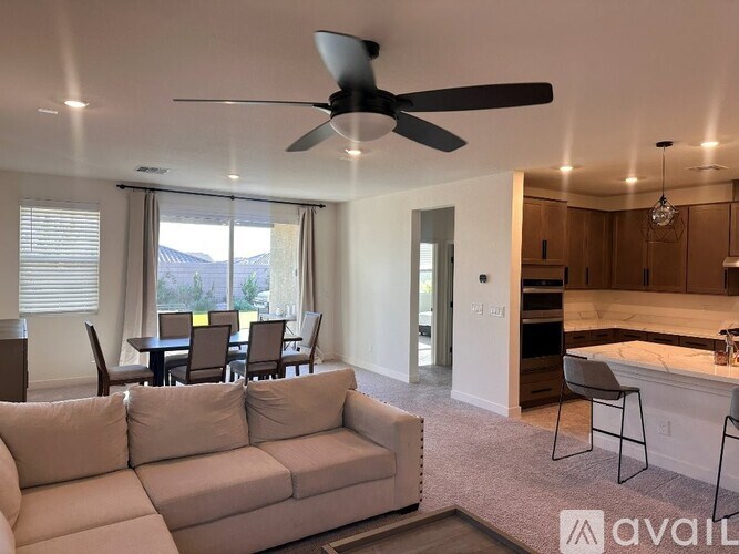 A living room with a couch, chairs, and a ceiling fan.