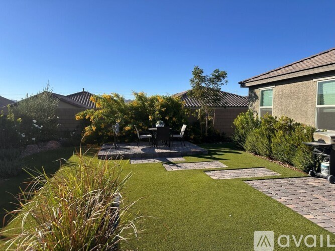 A backyard with a lawn, a patio, and a house.