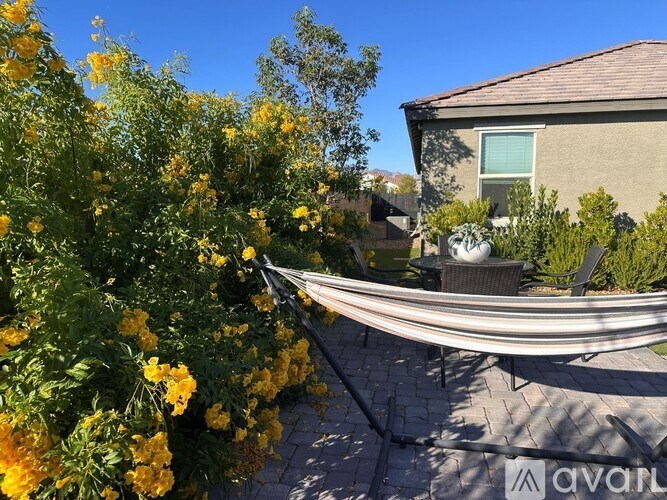 A patio with a hammock surrounded by yellow flowers.