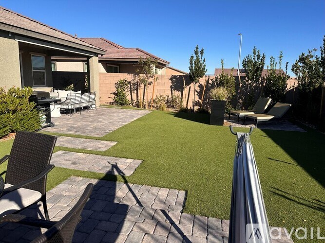A backyard with a lawn, patio furniture, and a house.