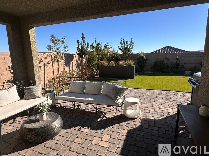 A patio with a white couch and a table with a vase on it.