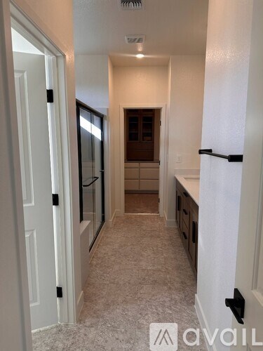 A hallway with a carpeted floor and white walls.