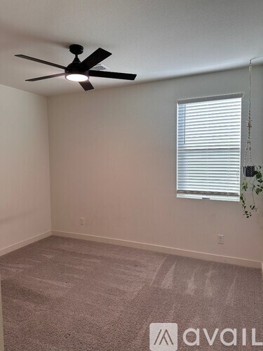 A room with a ceiling fan and a window with blinds.