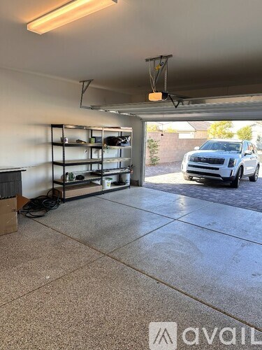 A garage with a white wall and a black car in the background.