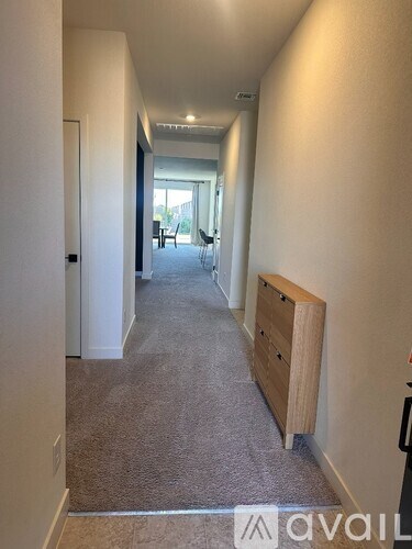 A long hallway with a carpeted floor and a door on the left.