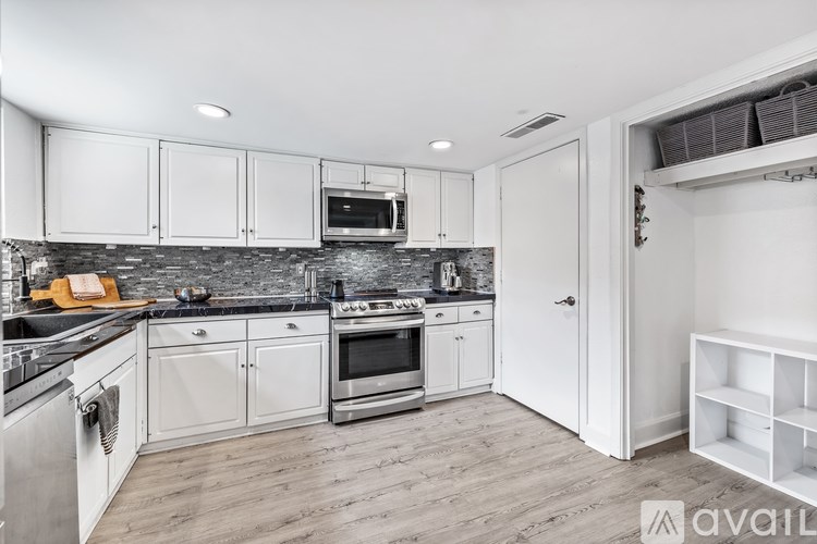 A kitchen with white cabinets and a black countertop.