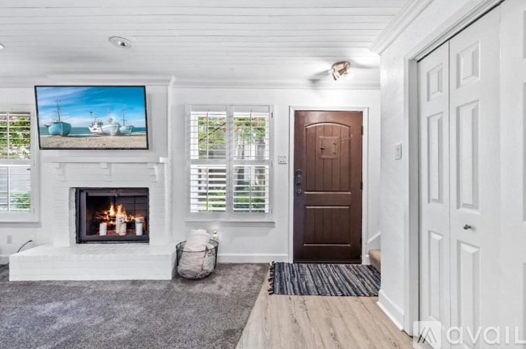 A cozy living room with a fireplace and a painting of a beach scene on the wall.