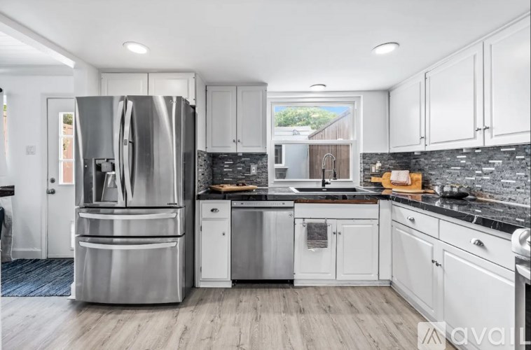 A modern kitchen with a stainless steel refrigerator and white cabinets.
