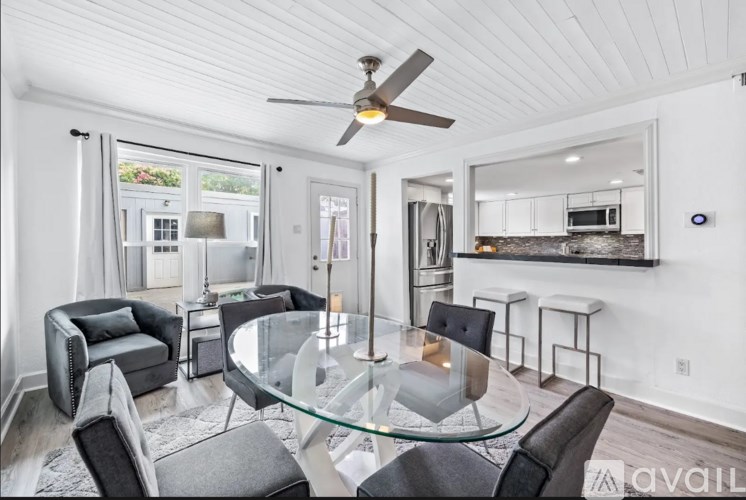 A modern living room with a glass table and black chairs.