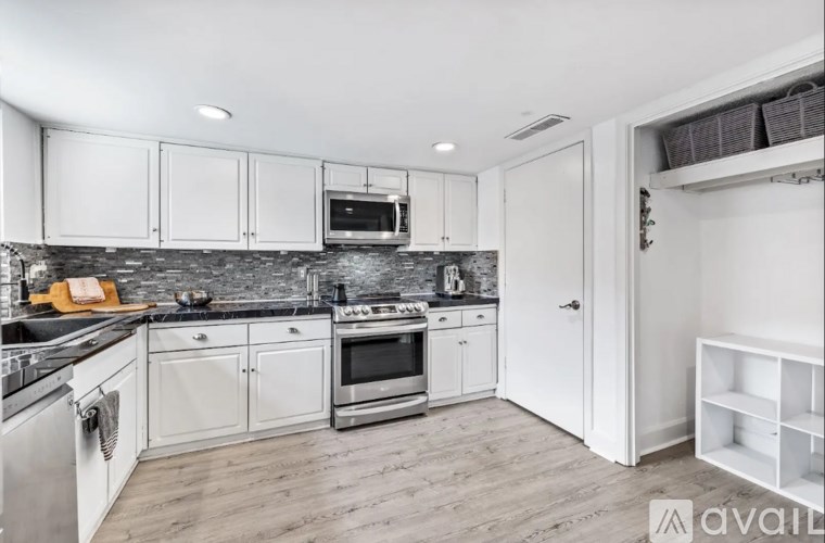 A kitchen with white cabinets and a black countertop.