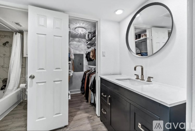 A bathroom with a white door and a round mirror above a sink.