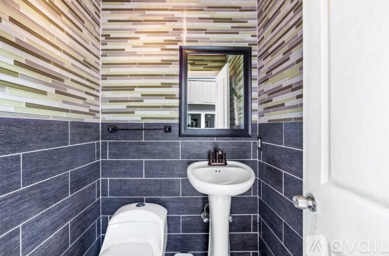 A bathroom with a toilet, sink, and mirror.