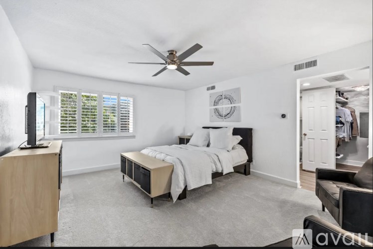 A bedroom with a bed, a dresser, and a ceiling fan.