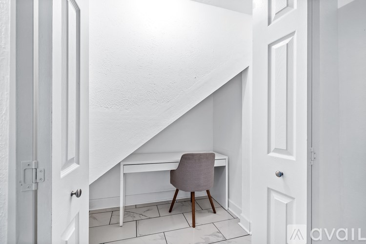 A small desk with a chair is tucked into a corner under a staircase.