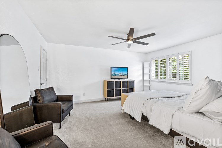 A bedroom with a bed, a chair, and a television.