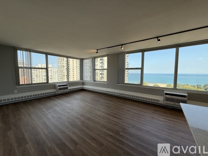A spacious room with wooden floors and large windows overlooking the city and sea.