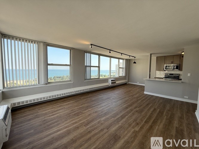 A spacious room with wooden flooring and large windows overlooking the beach.
