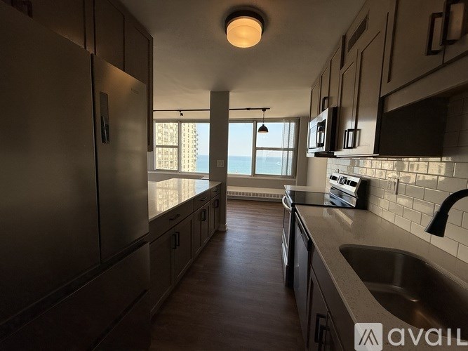 A modern kitchen with dark wood floors and stainless steel appliances.
