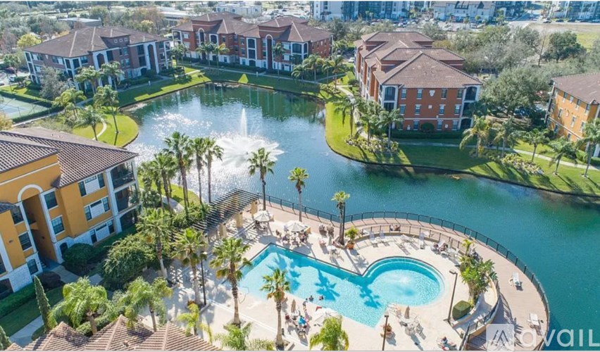 A pool surrounded by palm trees and a fountain in the middle of a resort.