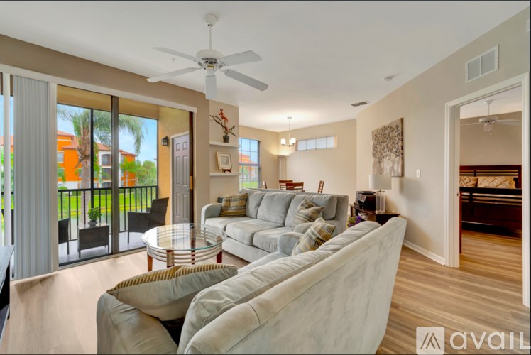 A spacious living room with a large couch and a ceiling fan.
