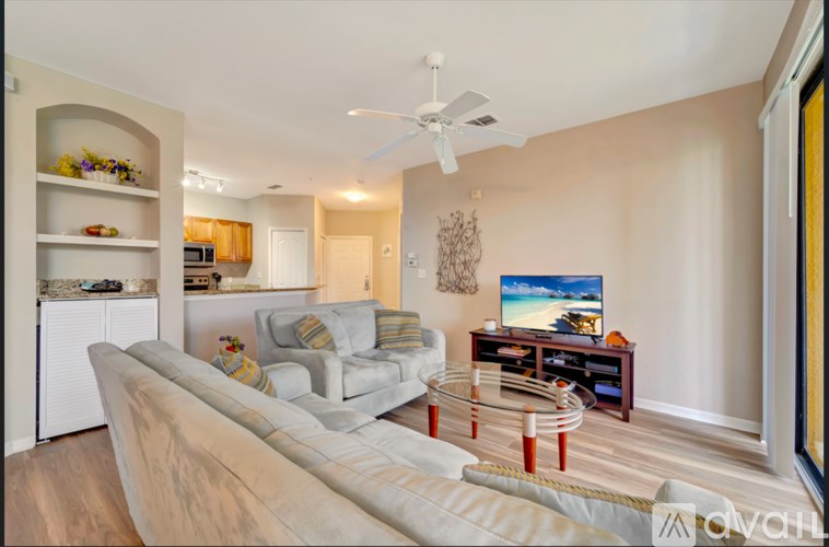 A living room with a white couch and a television on a stand.