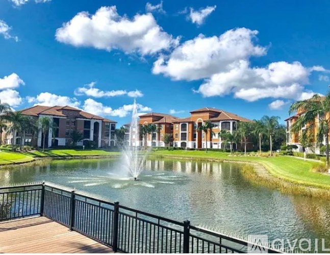 A fountain in the middle of a pond in front of a building.