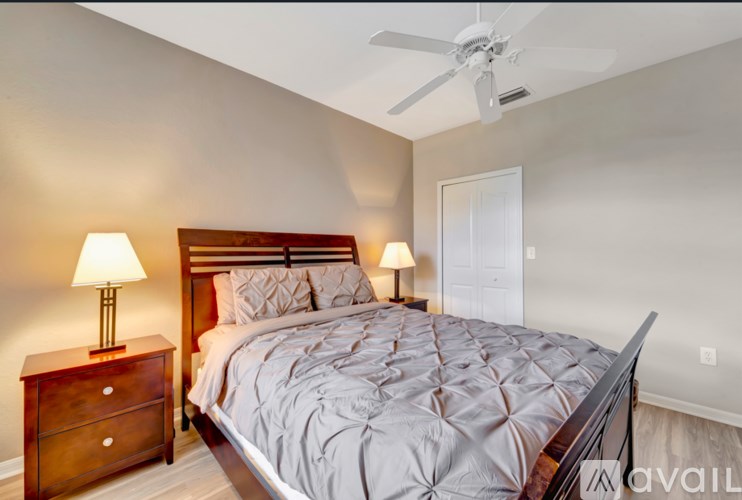A bedroom with a bed, two lamps, and a ceiling fan.