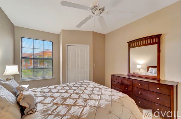 A bedroom with a large bed, a ceiling fan, and a view of a building outside the window.