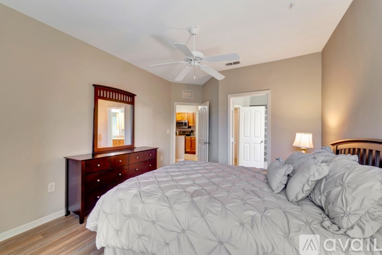A bedroom with a large bed and a dresser with a mirror above it.