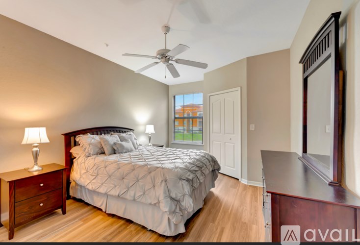 A bedroom with a large bed, a ceiling fan, and a wooden floor.