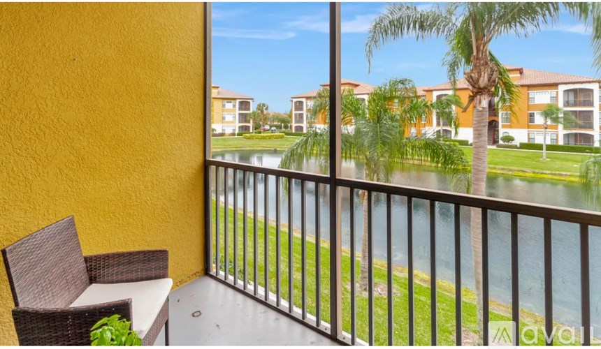 A balcony with a chair and a view of a pond and buildings.