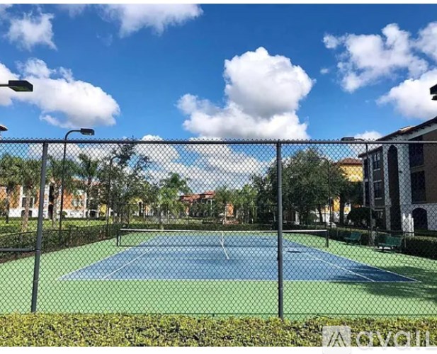 A tennis court surrounded by a fence and trees.