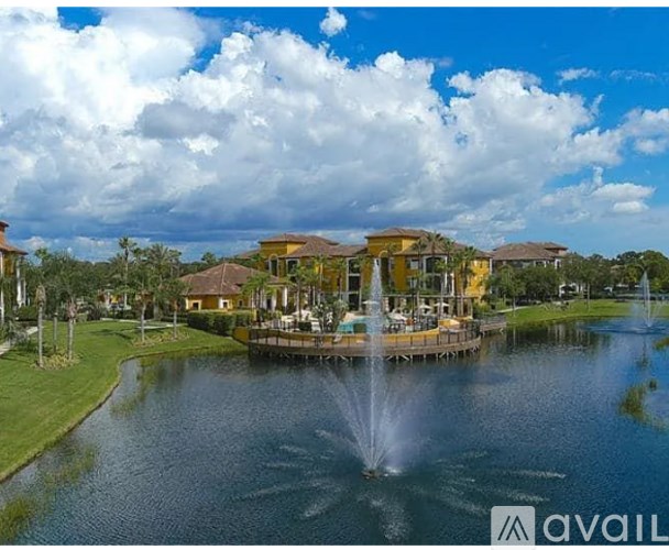A fountain in the middle of a lake in front of a building.