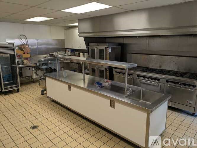 A clean, empty commercial kitchen with stainless steel appliances and white countertops.