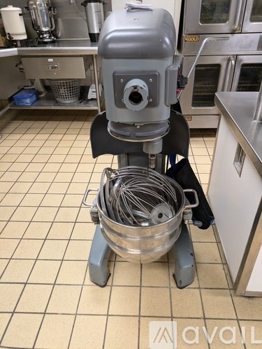 A mixer with a bowl full of whiskers on a kitchen floor.