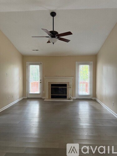 A spacious room with a fireplace and a ceiling fan.