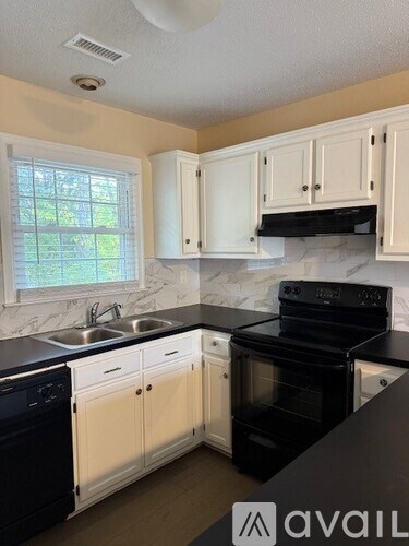 A kitchen with black appliances and white cabinets.