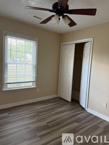 A room with a ceiling fan and a window with blinds.