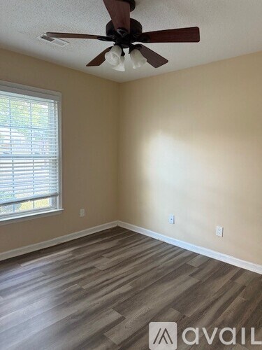 A room with a ceiling fan and wooden flooring.