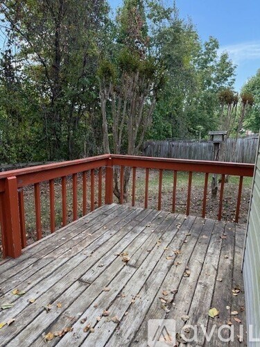 A wooden deck with a railing and trees in the background.