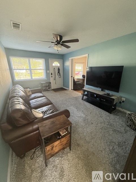 A living room with a brown leather couch and a flat screen TV.