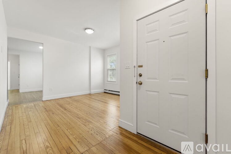 A room with a white door and wooden flooring.