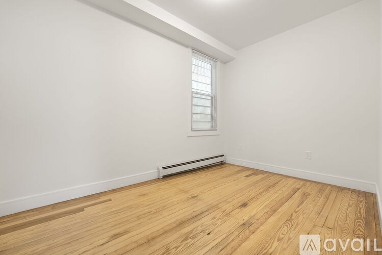 A room with wooden flooring and a window with blinds.