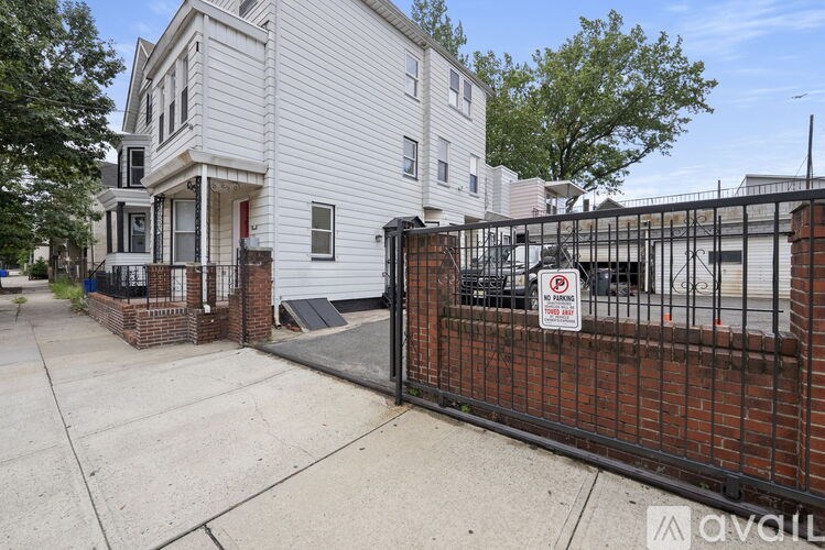 A white two-story house with a black fence in front.