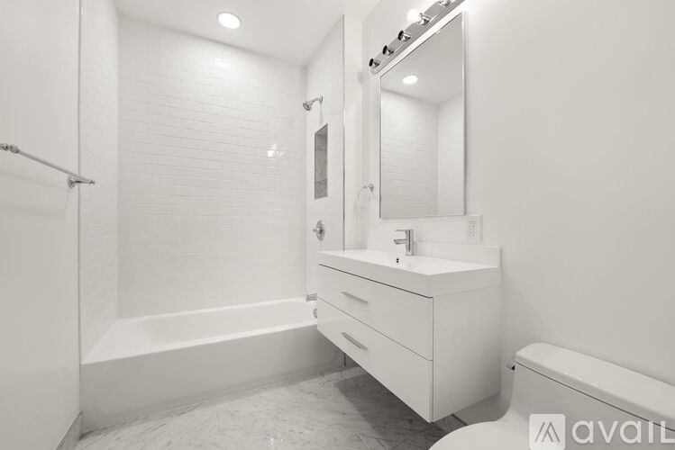 A white bathroom with a tub, sink, and mirror.