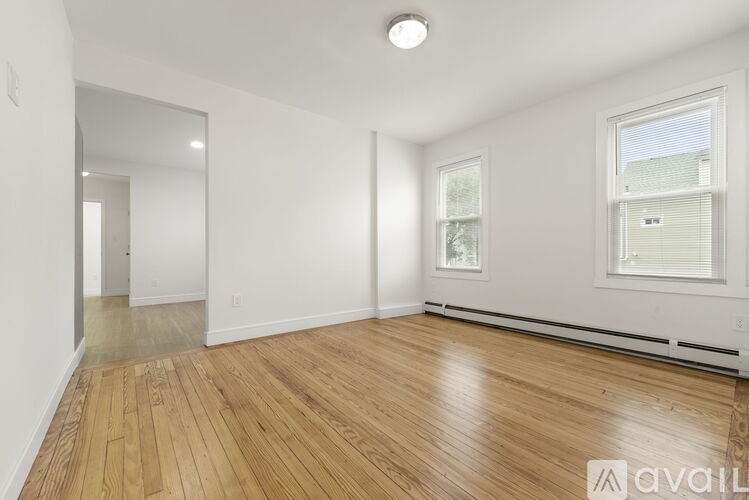 A room with wooden flooring and a window with blinds.