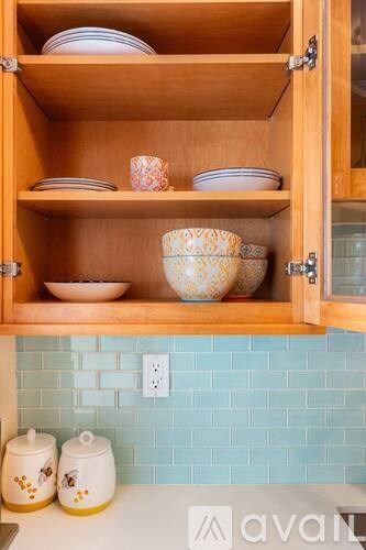 A kitchen cabinet with plates and bowls on the shelves.