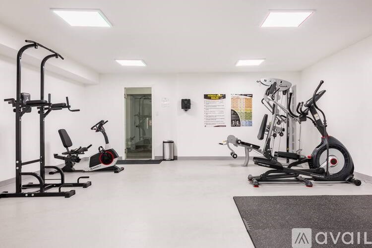 A gym with a variety of exercise equipment including a stationary bike, a rowing machine, and a weight bench.