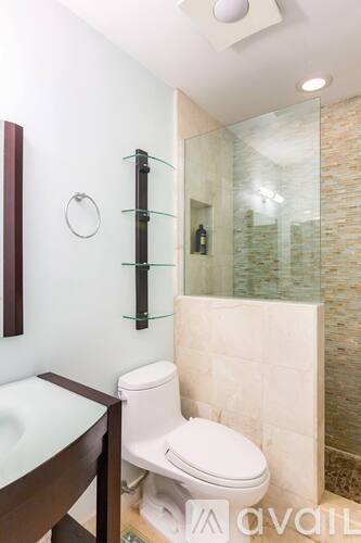 A white toilet sits in a bathroom with a glass shower door.